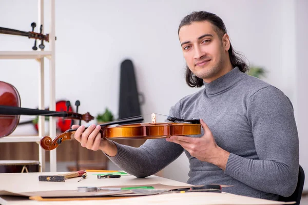 Young male repairman repairing violin