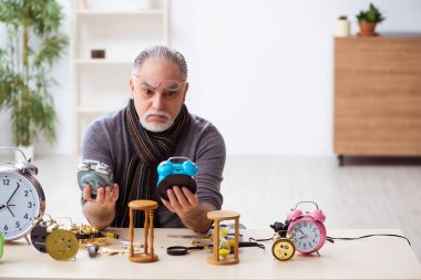 Atölyede çalışan yaşlı bir erkek saatçi.