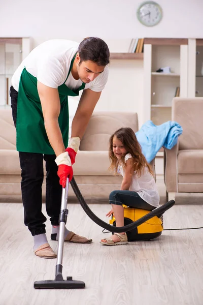 Jovem empreiteiro limpando a casa com sua filha pequena — Fotografia de Stock
