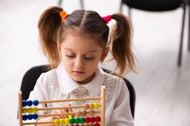 Sınıfta abaküsü olan küçük bir kız.