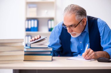 Kitap yazan yaşlı bir erkek yazar.