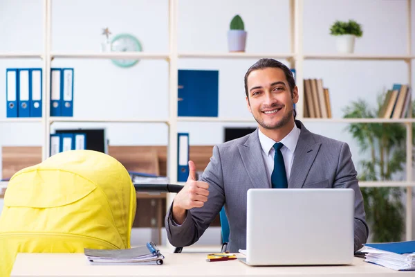 Joven empleado masculino que cuida del recién nacido en el lugar de trabajo — Foto de Stock