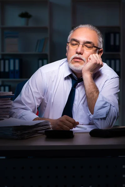 Oude mannelijke werknemer die laat op kantoor werkt — Stockfoto