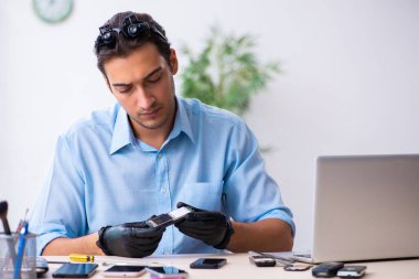 Cep telefonunu tamir eden genç bir teknisyen.