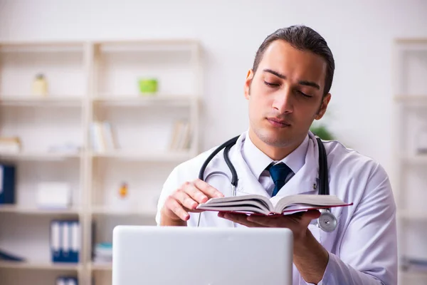 Young male student doctor reading book in the clinic