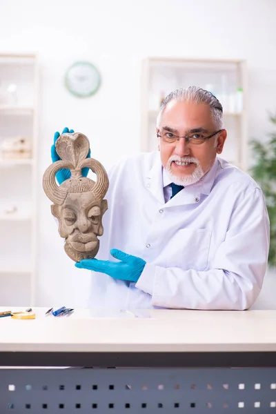 Eski Afrika taş maskesi üzerine çalışan kıdemli bir arkeolog. — Stok fotoğraf