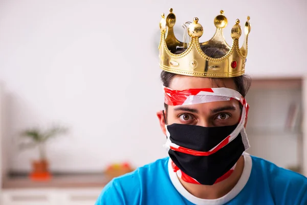 Junger Mann mit Krone auf dem Kopf zu Hause — Stockfoto