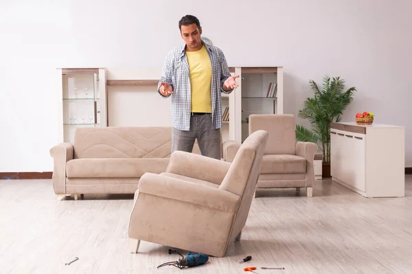 Young male carpenter repairing furniture at home