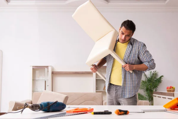 Young male carpenter repairing furniture at home