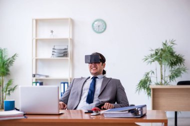 Ofiste sanal gözlük takan genç bir erkek çalışan.