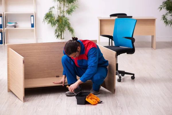 Молодий підрядник ремонтує меблі в офісі — стокове фото