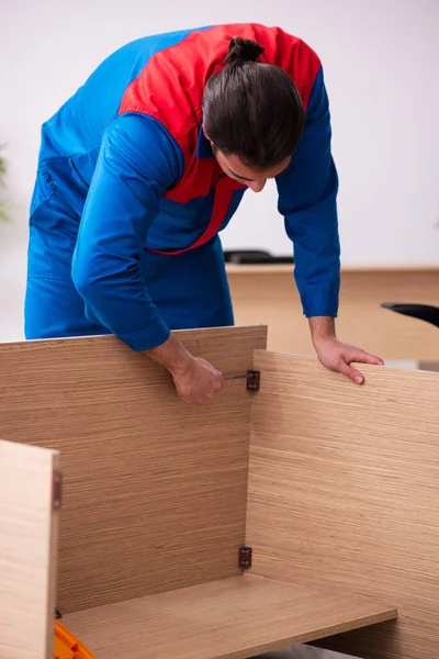 Young male contractor repairing furniture in the office