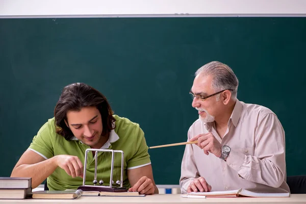 Старий професор фізик і молодий студент у класі — стокове фото