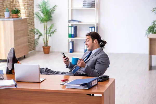 Young male employee drinking coffee in the office — Stock Photo, Image