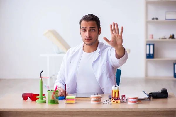 Jonge mannelijke tandarts werkzaam in de kliniek — Stockfoto