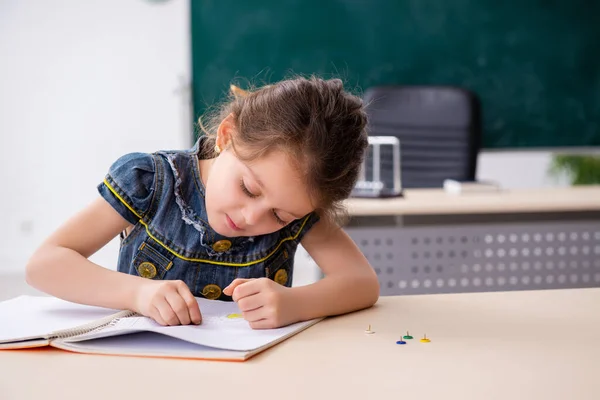 Small girl and thumbtacks in the classroom — Stock Photo, Image