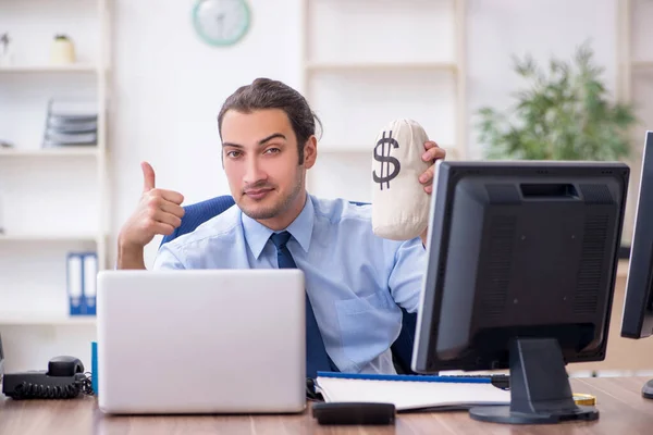 Молодой работник мужского пола держит мешок с деньгами в офисе — стоковое фото