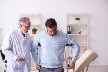 Genç bacağı yaralı adam yaşlı doktor osteopath 'ı ziyaret ediyor.