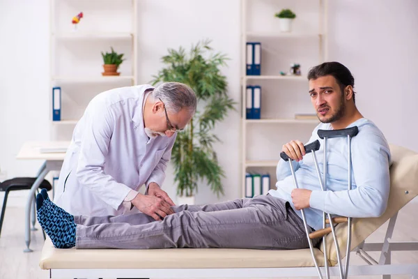Genç bacağı yaralı adam yaşlı doktor osteopath 'ı ziyaret ediyor. — Stok fotoğraf