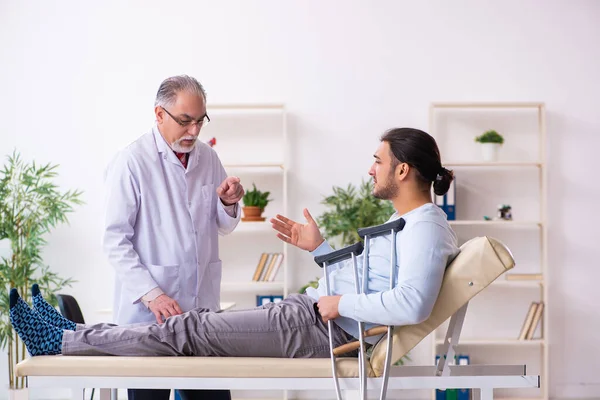 Genç bacağı yaralı adam yaşlı doktor osteopath 'ı ziyaret ediyor. — Stok fotoğraf