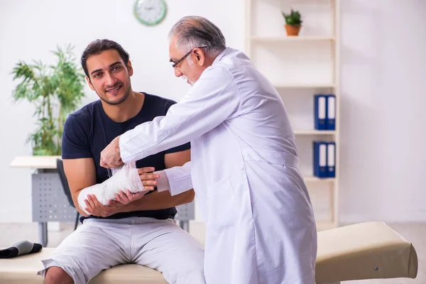 Genç yaralı adam deneyimli erkek doktor travmatologları ziyaret ediyor. — Stok fotoğraf