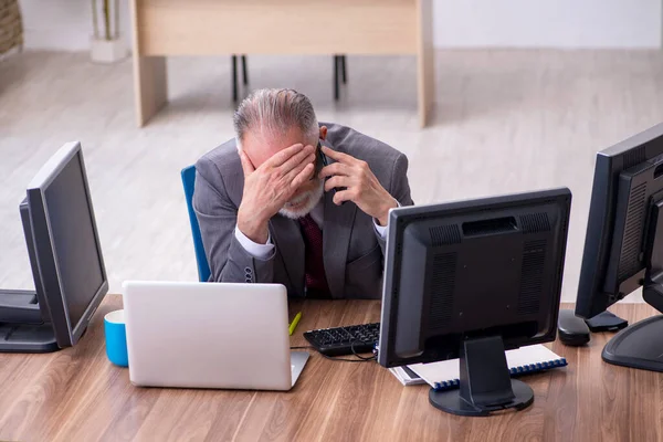 Velho chefe masculino sentado na área de trabalho no escritório — Fotografia de Stock