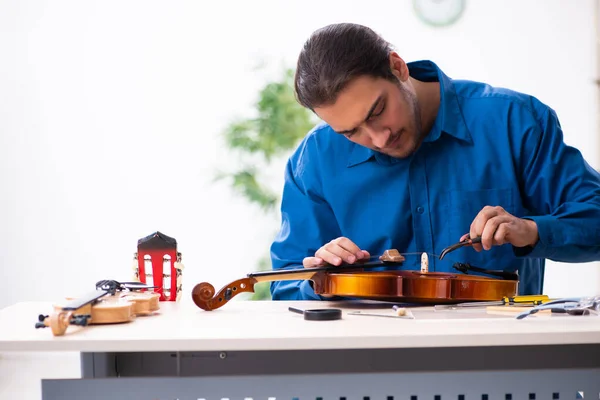 Young male repairman repairing violin