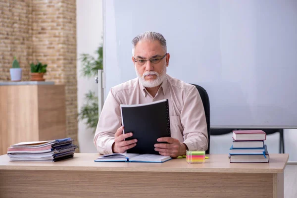 Vecchio insegnante di sesso maschile seduto in classe — Foto Stock