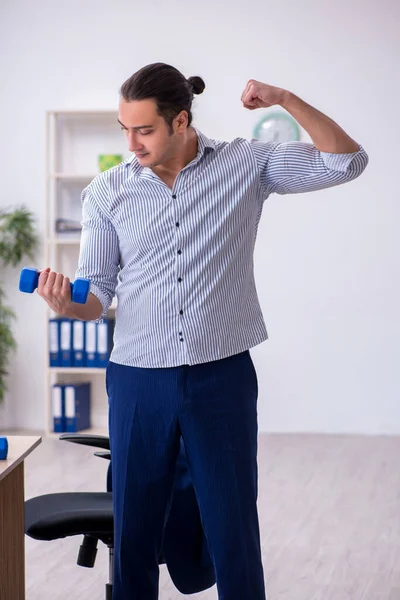 Jovem bonito masculino empregado fazendo exercícios no escritório — Fotografia de Stock