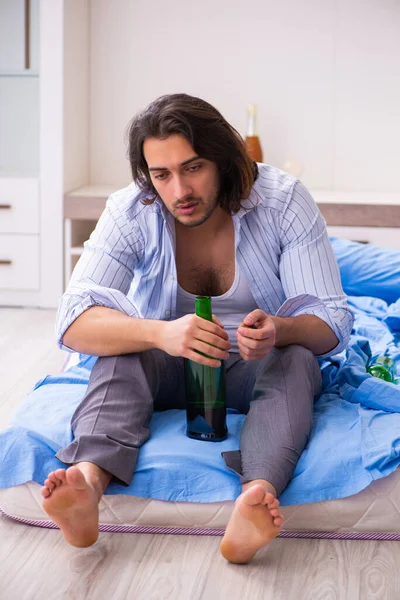 Junger männlicher Alkoholiker im Schlafzimmer — Stockfoto