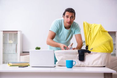 Genç erkek ebeveyn yeni doğan bebeğe evde bakıyor.