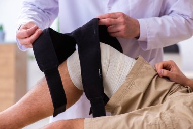Deneyimli doktor travmatolog genç erkek hastayı muayene ediyor.