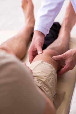Deneyimli doktor travmatolog genç erkek hastayı muayene ediyor.