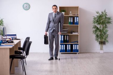 Ofiste çalışan genç bacağı yaralı bir erkek işçi.