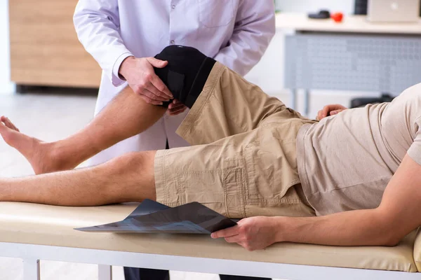 Médico traumatólogo experimentado examinando paciente varón joven — Foto de Stock