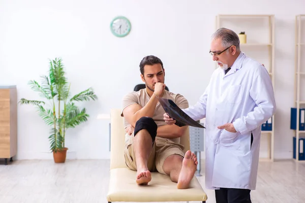 Médico radiólogo experimentado examinando paciente varón joven — Foto de Stock