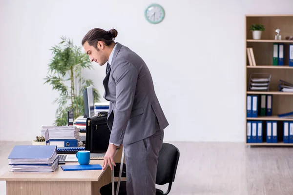 Jeune homme blessé à la jambe travaillant au bureau — Photo