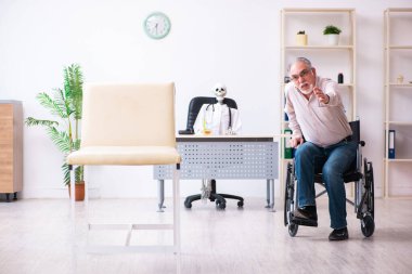 Tekerlekli sandalyedeki yaşlı adam ölü doktoru ziyaret ediyor.