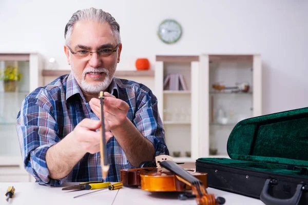Reparador sênior do sexo masculino reparando instrumentos musicais em casa — Fotografia de Stock