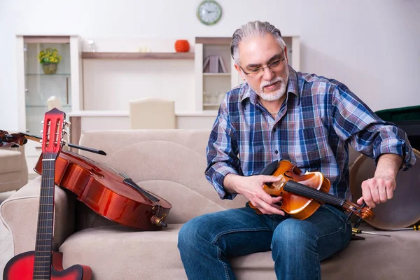 Hombre mayor reparador reparando instrumentos musicales en casa — Foto de Stock