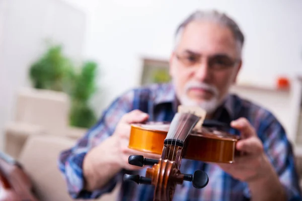 Réparateur masculin senior réparant des instruments de musique à la maison — Photo