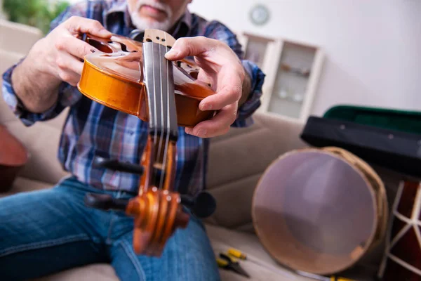Réparateur masculin senior réparant des instruments de musique à la maison — Photo