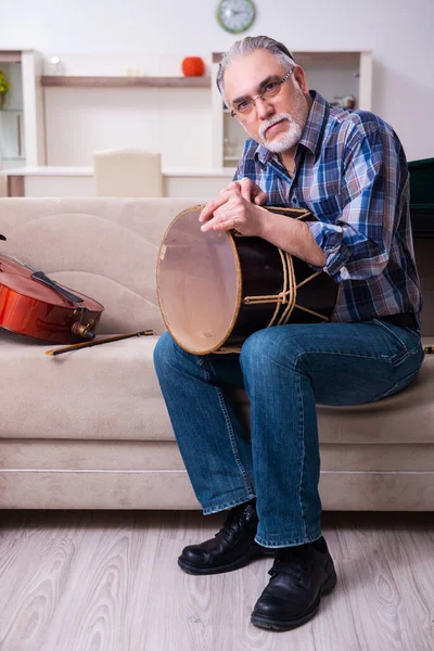 Senior mannelijke reparateur die thuis muziekinstrumenten repareert — Stockfoto