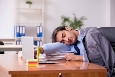 Genç erkek çalışan ofiste uyuyor.