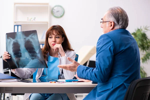 Gammal affärsman besöker ung kvinnlig läkare — Stockfoto