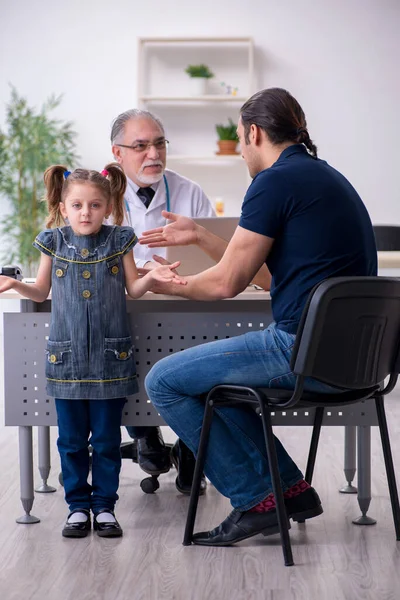 Genç baba ve kızı yaşlı doktoru ziyaret ediyor. — Stok fotoğraf