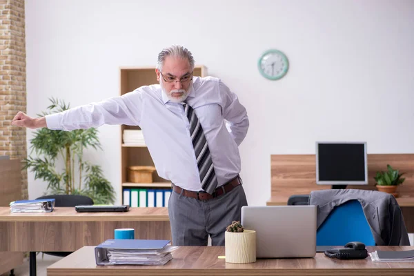 Velho trabalhador masculino que sofre de radiculite no local de trabalho — Fotografia de Stock