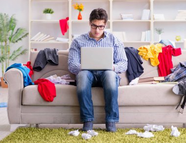 Genç adam dağınık bir odada çalışıyor.