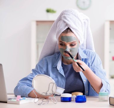 Kadın evde fırçayla kilden maske takıyor