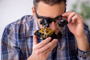 Genç erkek saatçi atölyede çalışıyor.